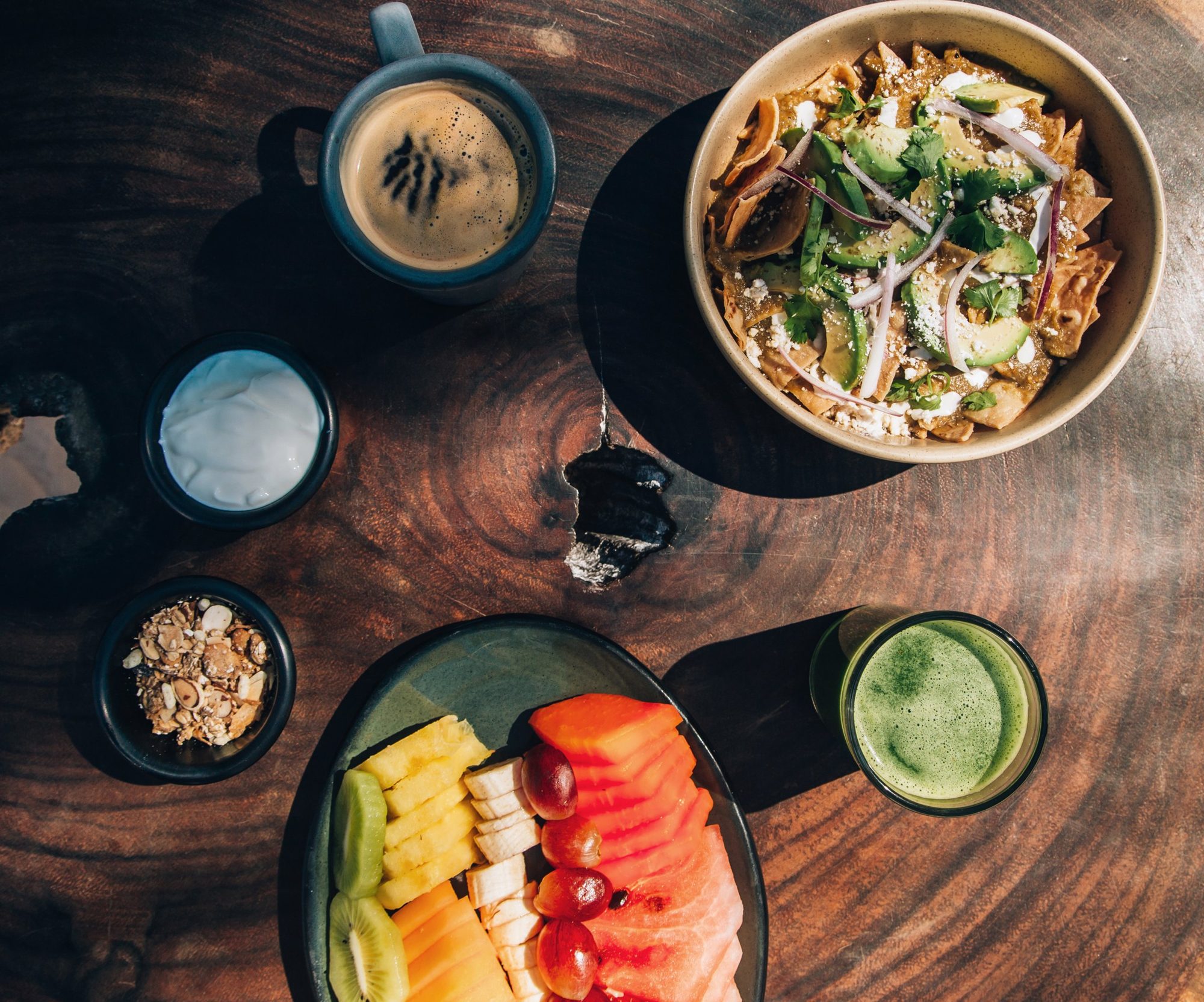 Mesa de desayuno: chilaquiles, fruta y café